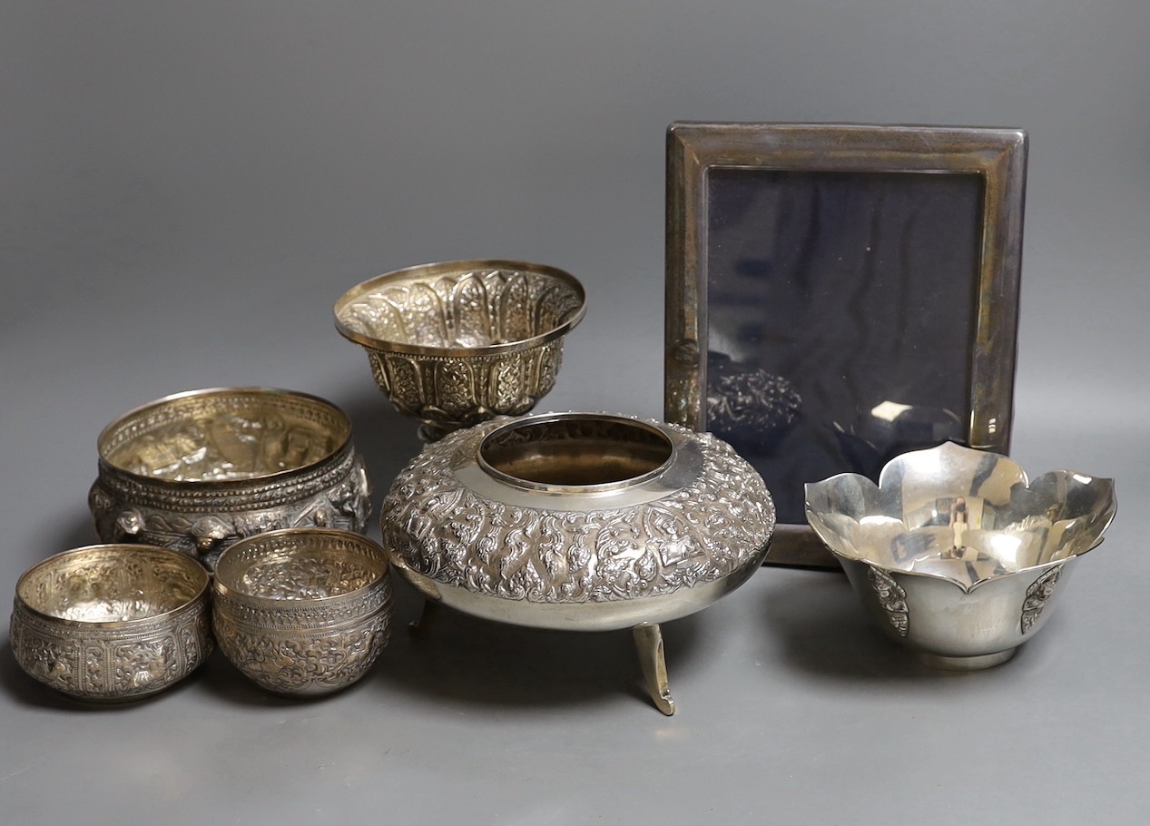 Six assorted embossed Thai white metal bowls, largest 18cm diam., and a silver photograph frame